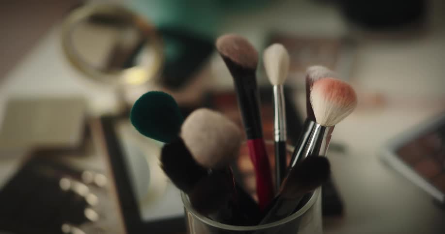 A person lifts a brush from a makeup kit