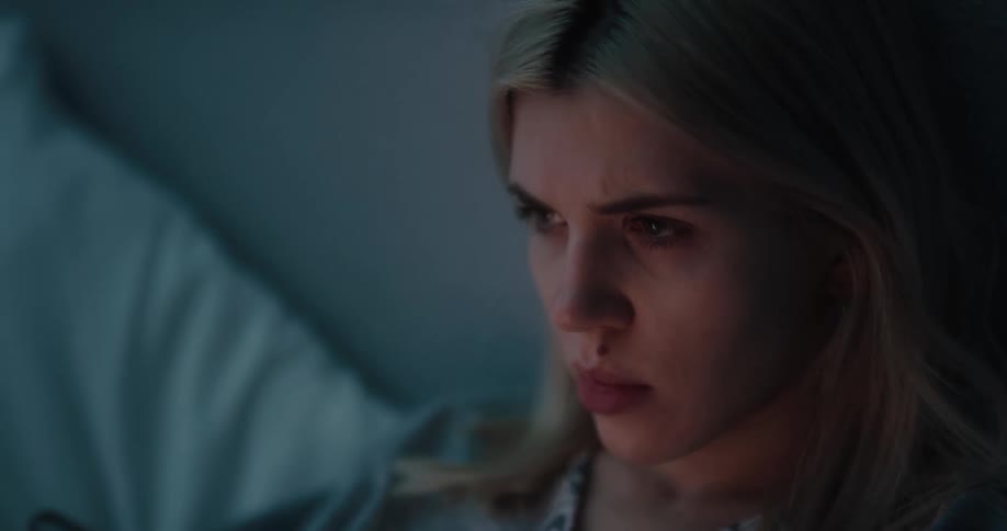 A woman laying in bed using a smartphone