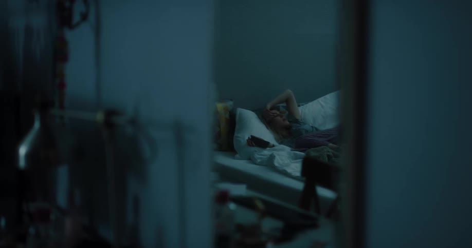 Mirror reflectiong of a young white woman lying down in her bed and using her smartphone