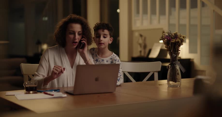 Mother being distracted by her son while working on her laptop