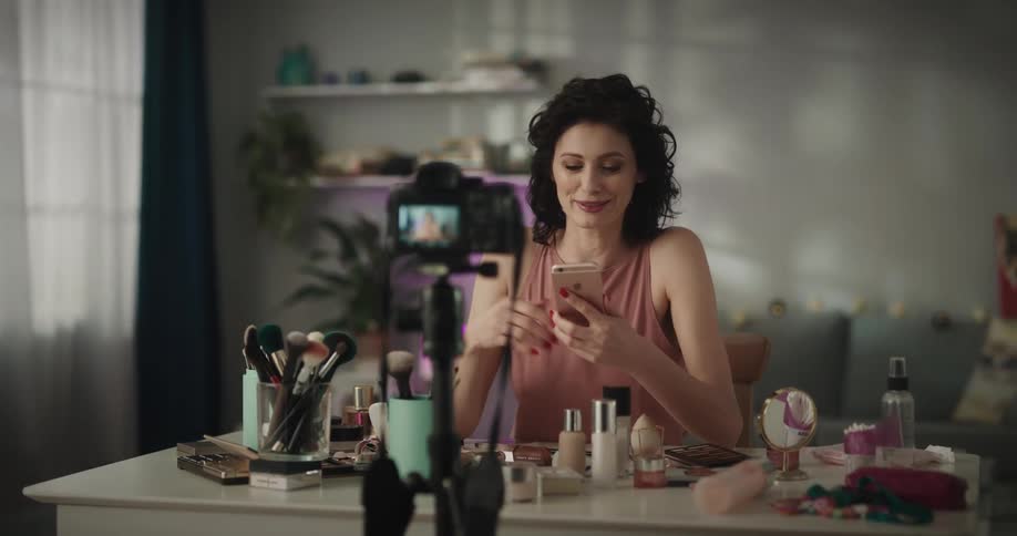 Woman sits at table using mobile phone on camera
