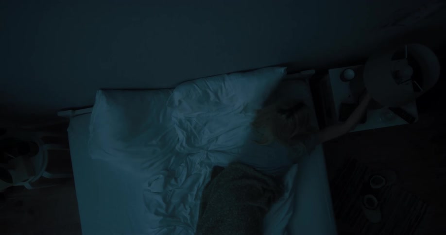 Young white woman sleeping in her bed then waking up and turning the table lamp on