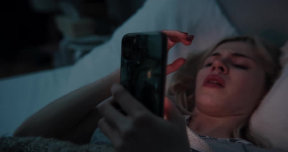 A woman uses her cell phone in bed