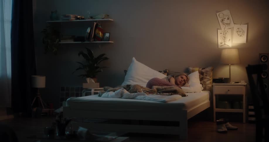 A woman is laying down on her bed