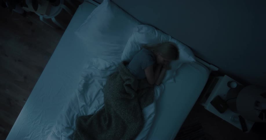 Young white woman sleeping in her bed on her bedroom during night