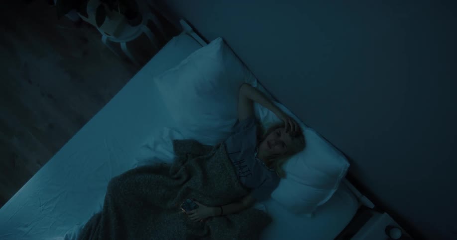 A woman is laying down and looking at a cellphone