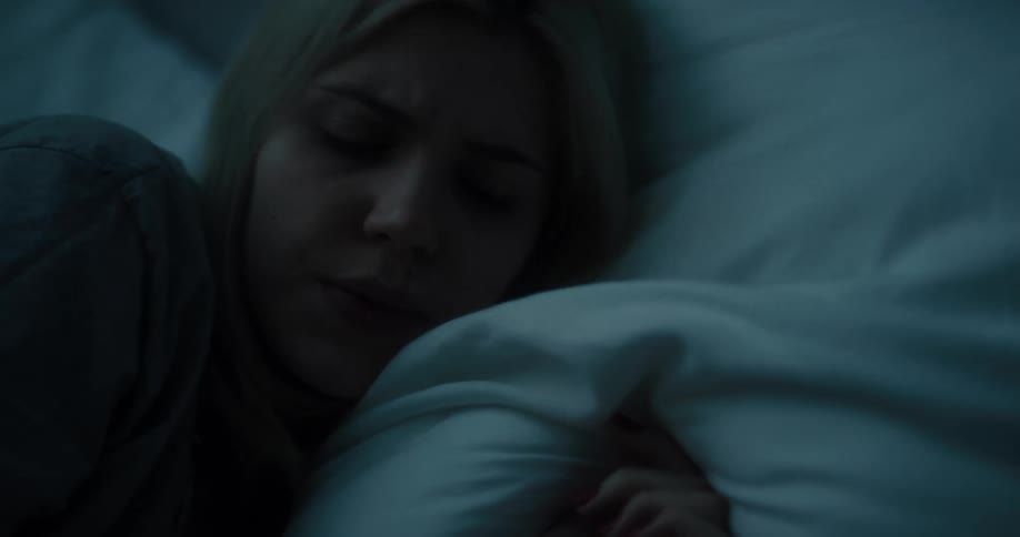 A woman is texting and laying down in a bedroom
