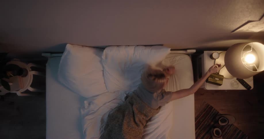 A woman turns off her bedside lamp and goes to sleep