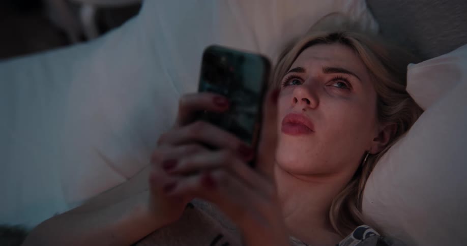 A woman is laying down and texting on a cellphone