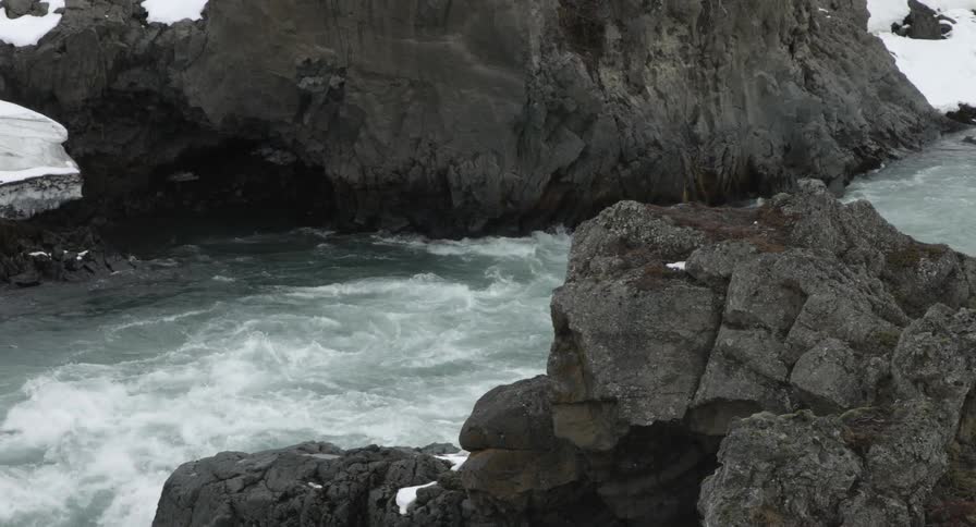 A river near a snowy, rocky shore