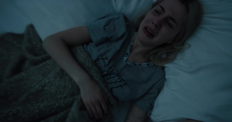 Teenaged girl lays in bed and looks at her cell phone then puts the phone under a pillow and starts crying