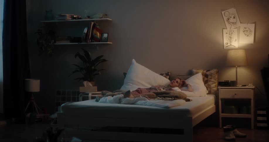 Young white woman lying down in bed at her bedroom looking to the ceiling with a bored face