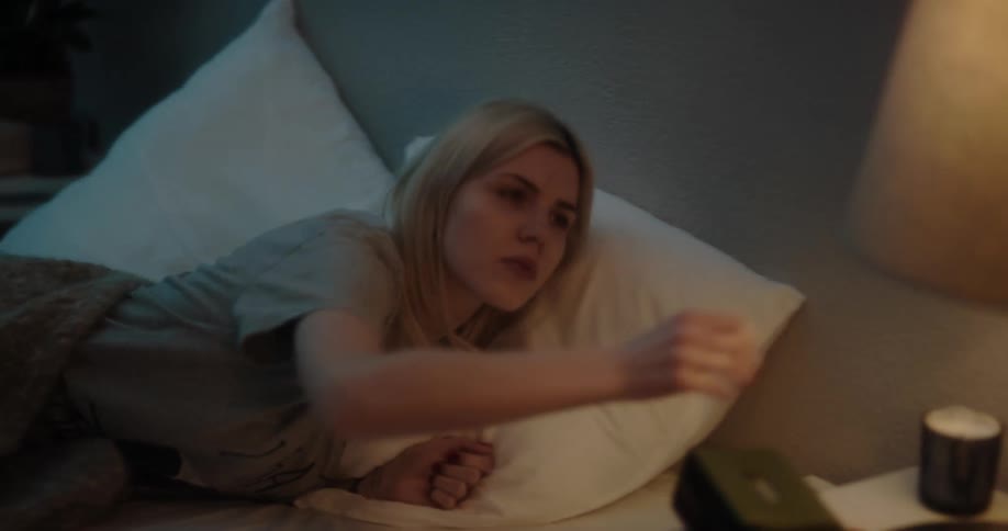 A woman texts on her phone before turning off the light and going to bed