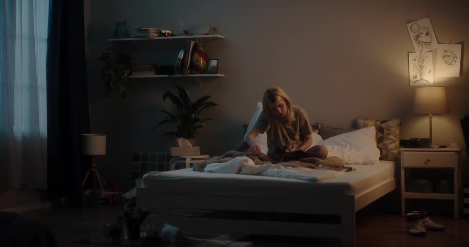 A woman is sitting in her bedroom and reading magazines