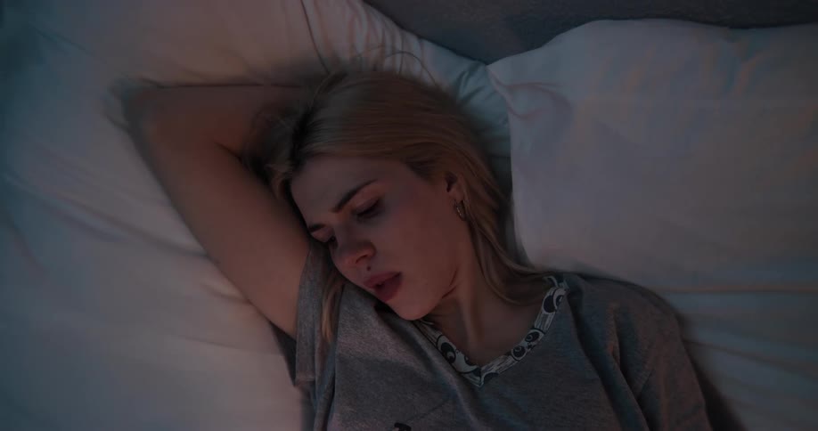 A woman is laying in bed and texting on a cellphone