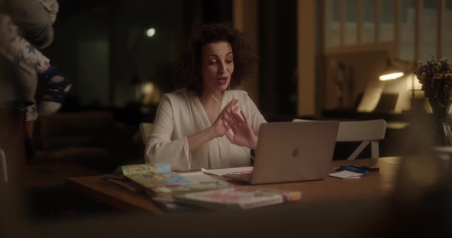 Father carrying the son out of the table after the mother complains about the noise when she is in the middle of a work related video call on her laptop