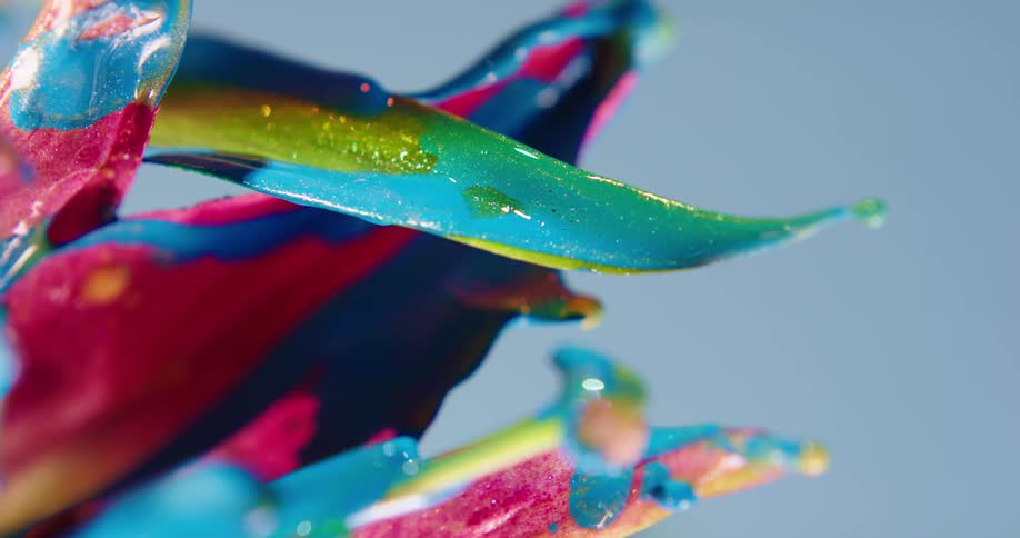 Colorful rainbow liquid glitter shimmering ink drips sideways from an abstract sculpture