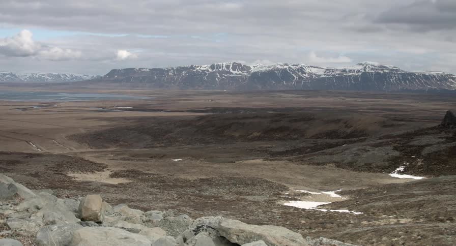View of a hilly field with mountains in the distance