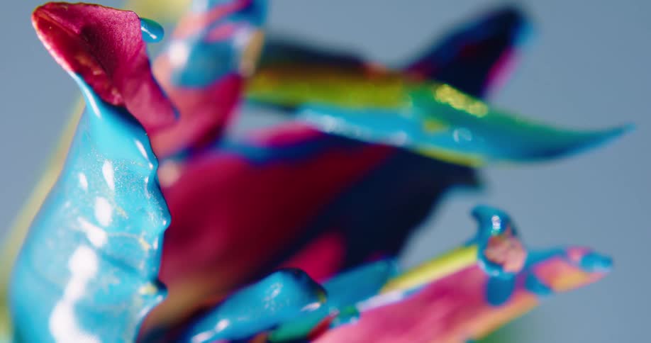 Colorful rainbow liquid glitter shimmering ink drips sideways from a flower