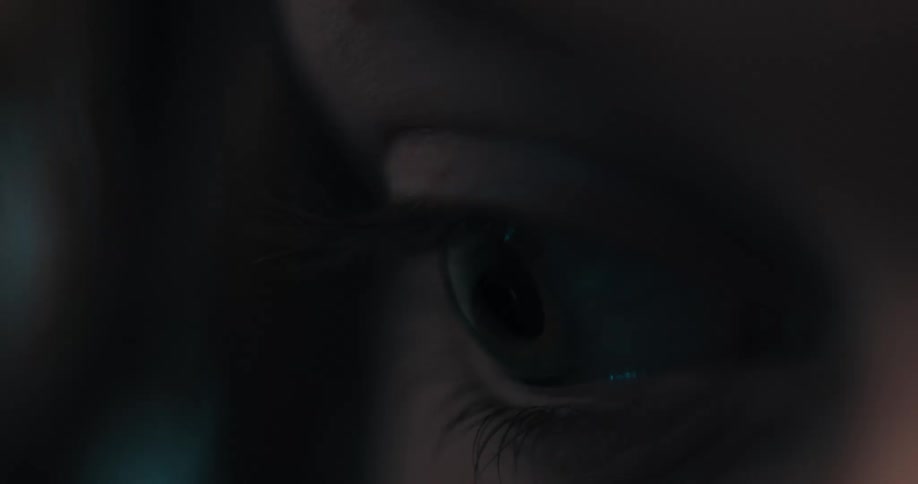 A woman closes her eyes while in a dark room