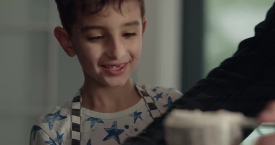 A boy pours flour in a sifter for his mom