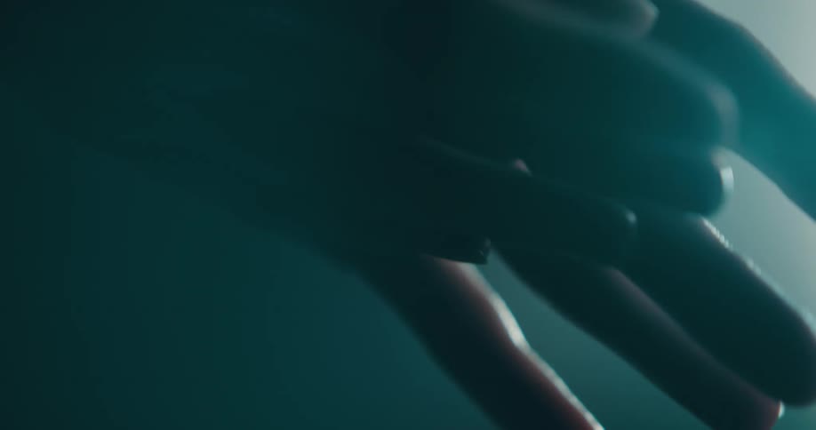 Hands moving around and gently touching each other with a light coming from the background
