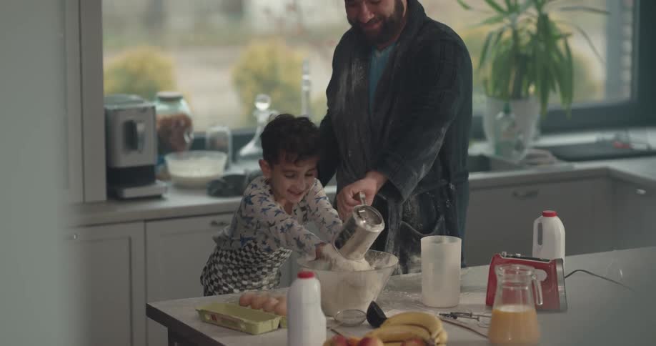 A father and son throw flower all around the kitchen