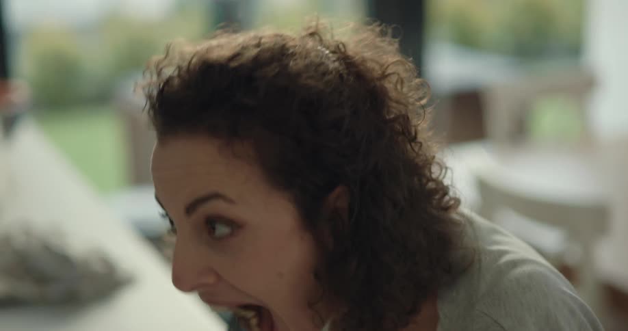 A woman makes happy noises and faces while eating and feeds her husband a bite
