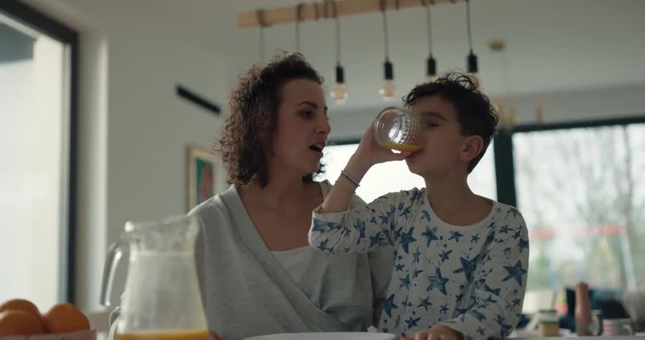A boy drinks a glass of orange juice