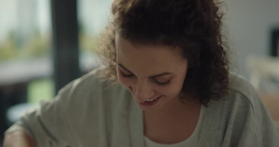 A man pours syrup on his wifes pancakes and she smiles as she eats breakfast