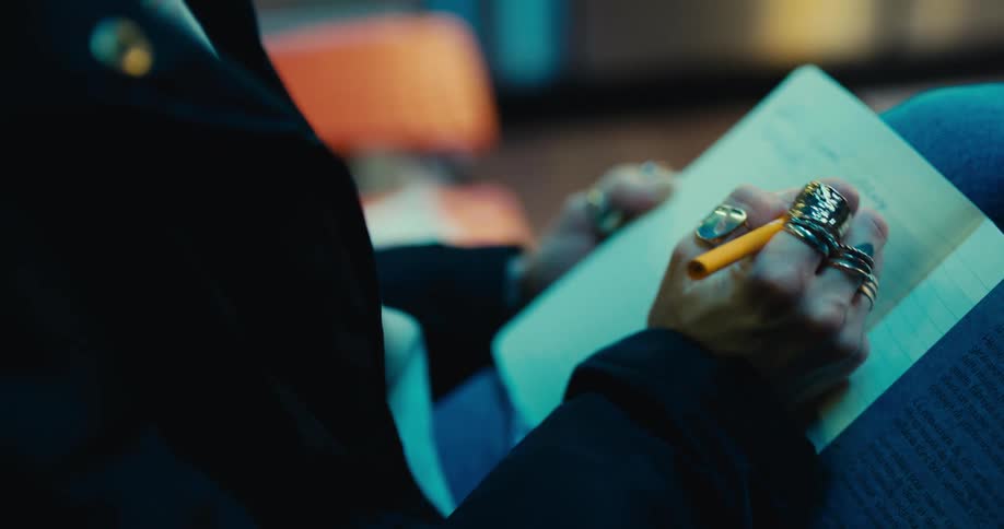 A woman sitting in a laundromat writing in a journal notebook
