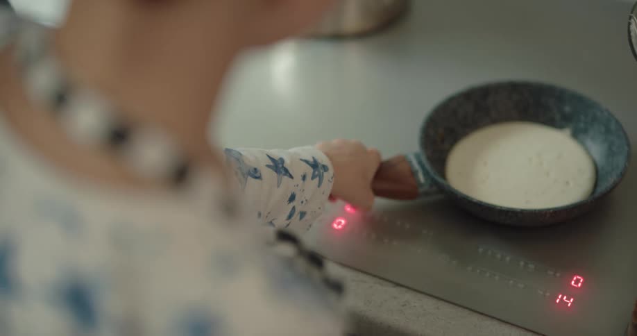 Father teaching his son how to cook pancakes in the kitchen at home