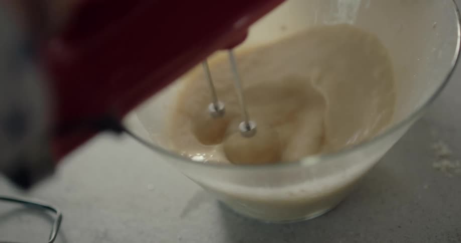 A dad holds the electric mixer steady for his son as they make breakfast together