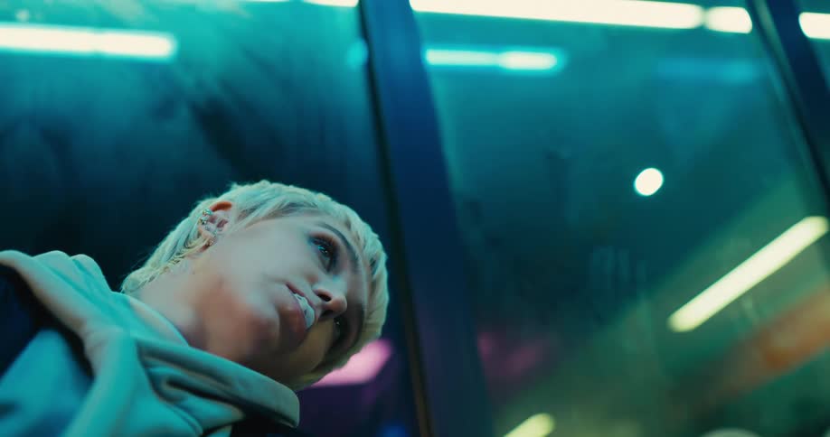 A woman is sitting indoors next to a window at night