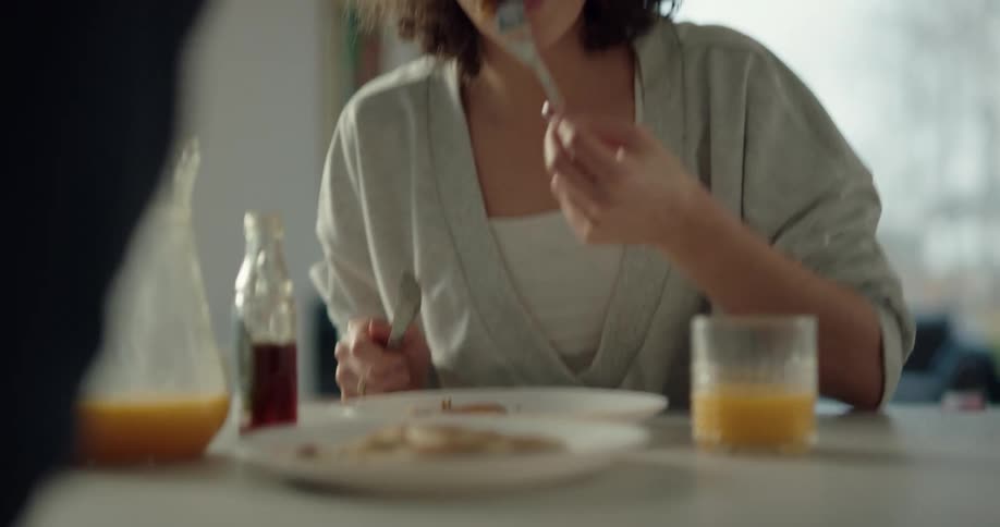 Happy relaxed woman eating breakfast with her husband at home in the morning