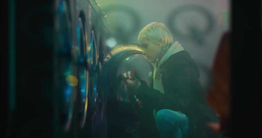 A woman is washing her clothes in the laundromat
