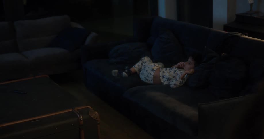 Young boy wearing pajamas watching television on the couch at home at night
