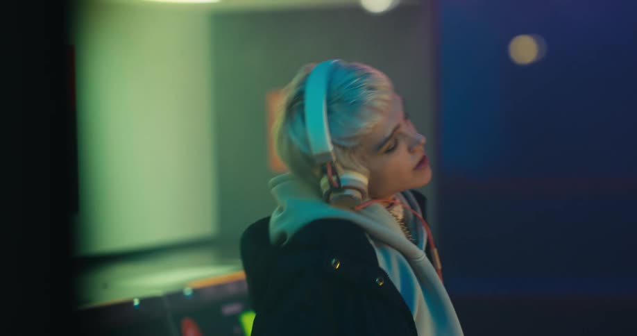 A woman wearing headphones dances around in a laundromat