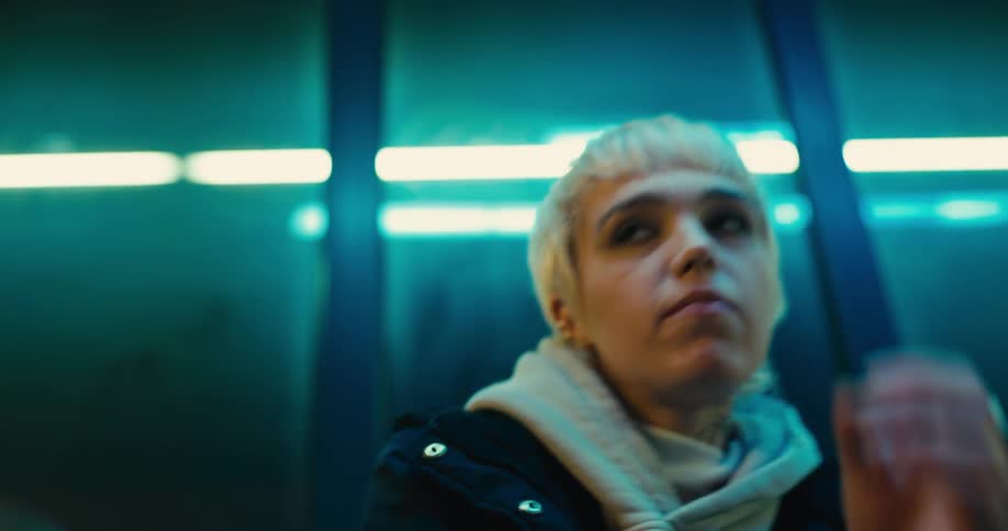 A bored looking woman chewing gum and sitting next to windows