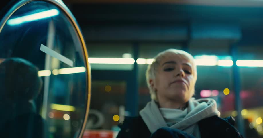 A woman enters the laundromat and loads her laundry into the machine