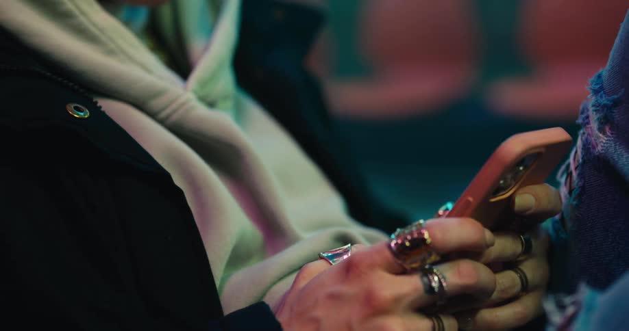 A woman is standing outdoors at night and texting