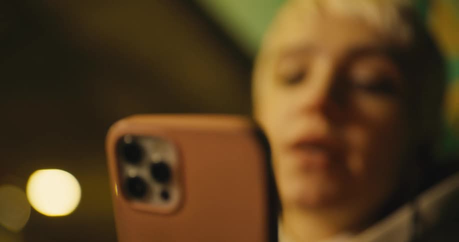 Young white woman wearing a earphone sitting outdoors and arguing with someone on a video call on her smartphone