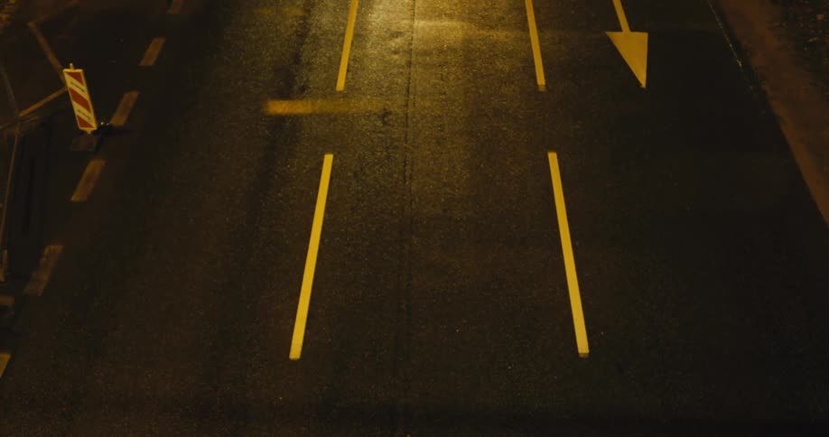 Vehicles drive along street with lane dividers and traffic symbols painted in yellow