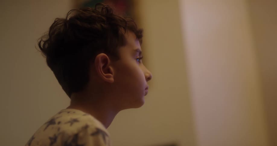 Boy wearing pajamas inside a house sitting down and then standing up