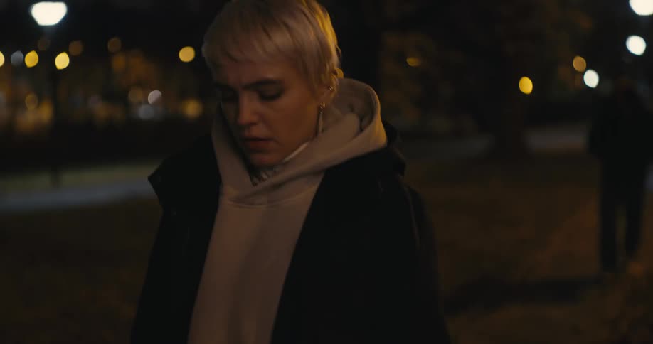 A man is following a woman outdoors at night