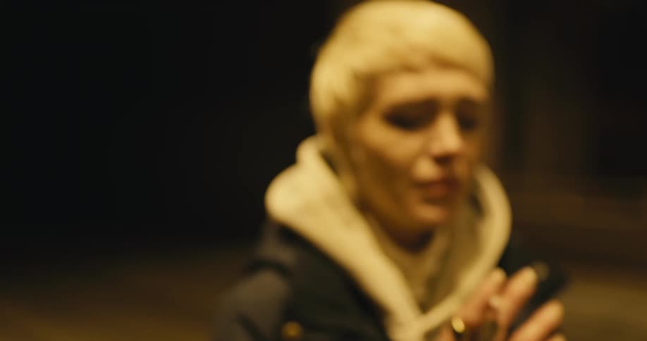 A woman is standing outdoors at night and smoking