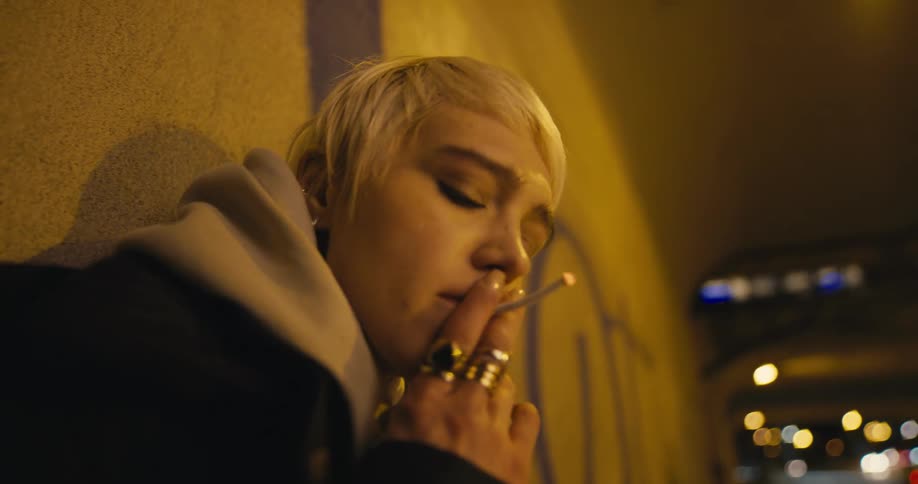A woman is outdoors at night smoking