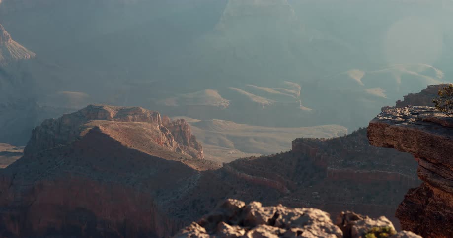 The sun shines brightly on a mountain ridge with mountains in the distance