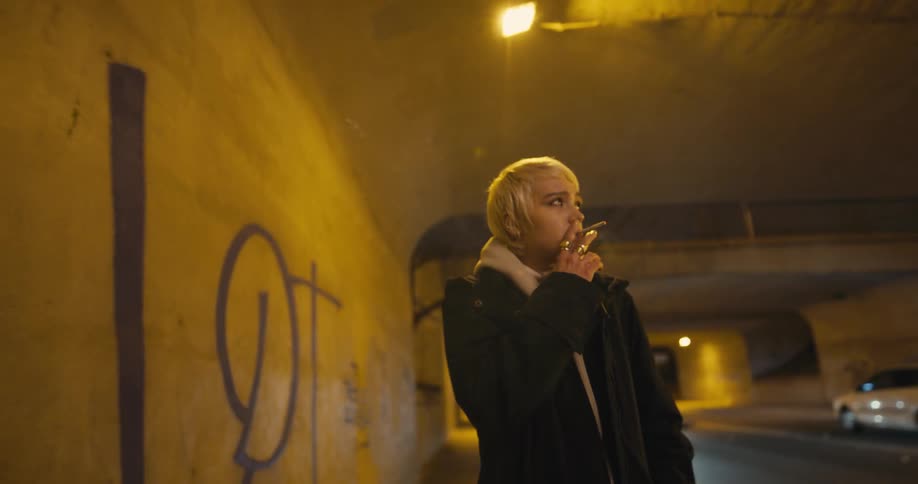 A woman walking next to a road at night
