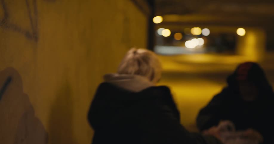 Young blonde woman walking out of an alley at night gets her purse stolen
